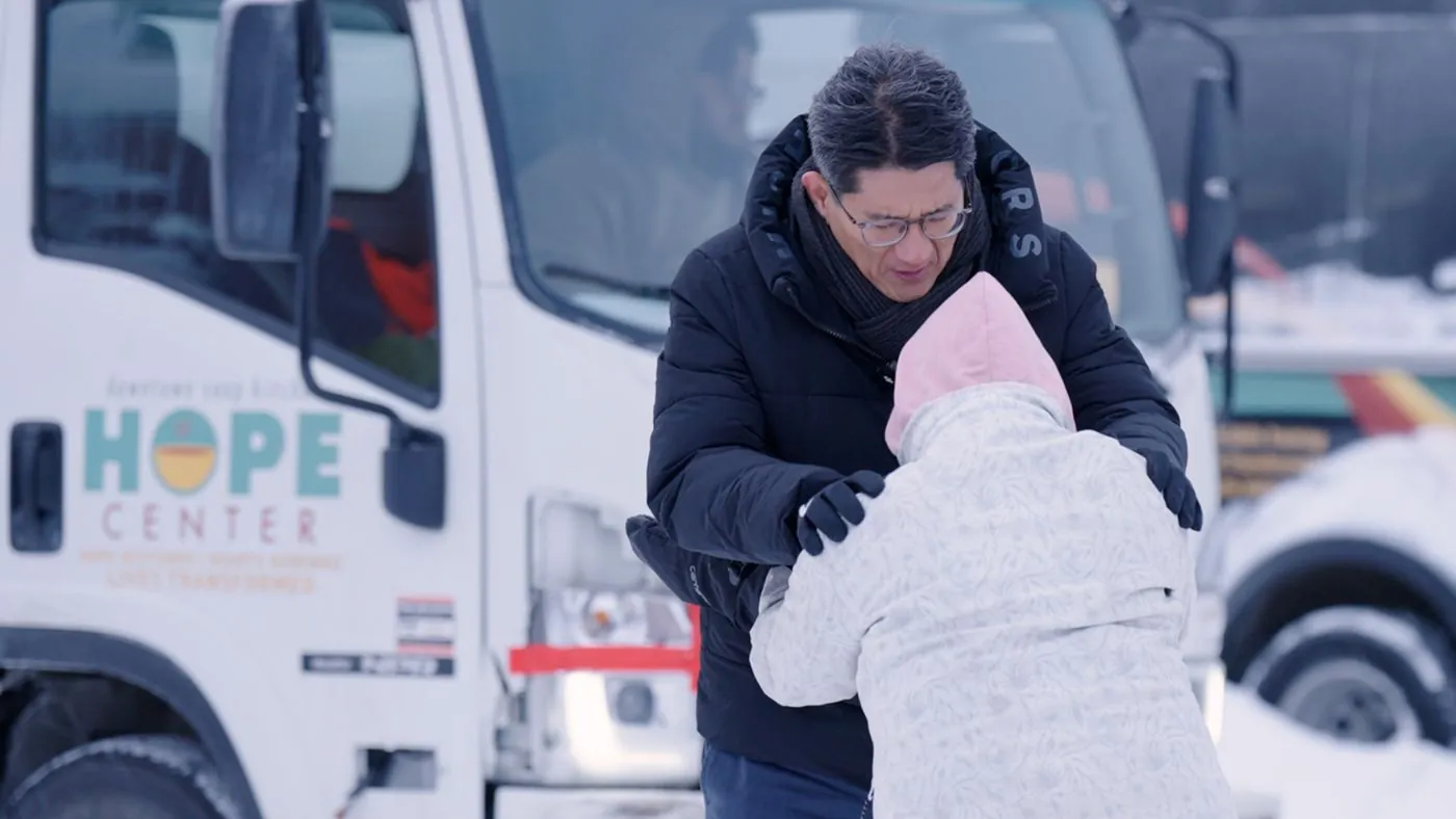 A missionary praying with a woman in the Alaska snow